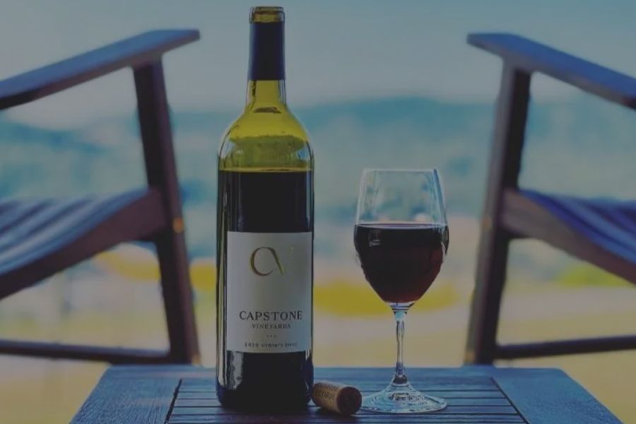 Bottle and glass of Capstone Vineyards red wine overlooking a scenic landscape