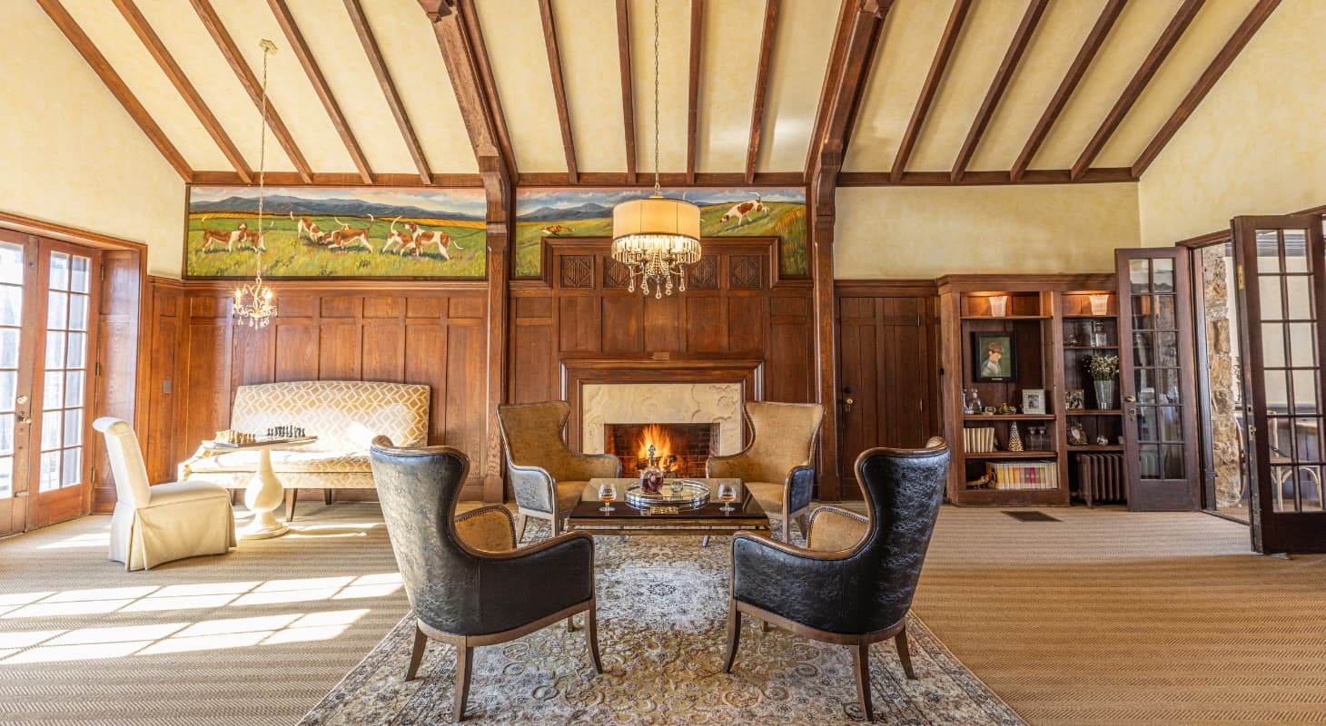 Grand wood-paneled common room with fireplace and fox hunt mural