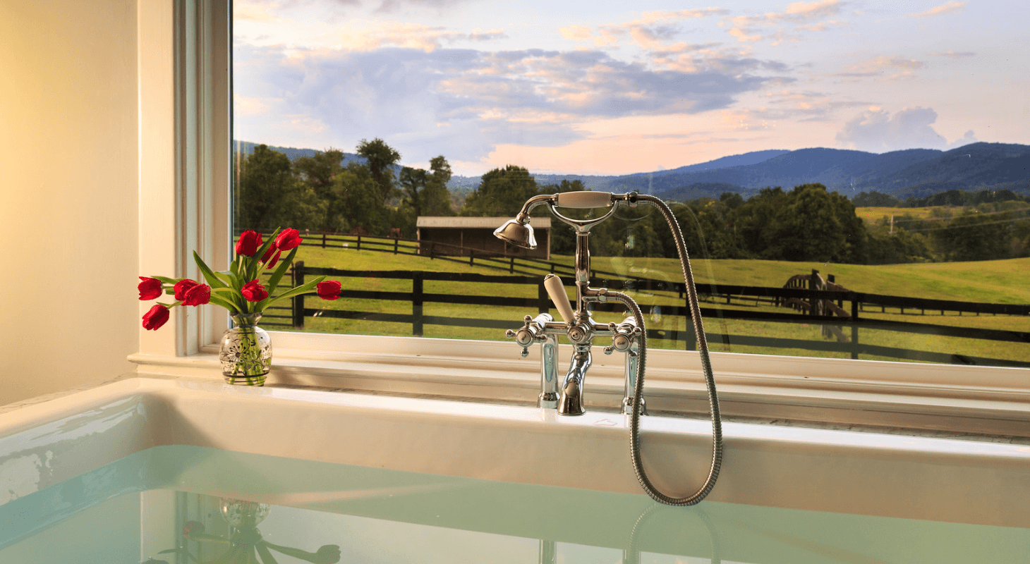 Soaking tub with a view of rolling hills and sunset