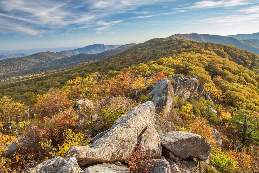 A large rock formation on top of a mountain with lots of fall foliage.