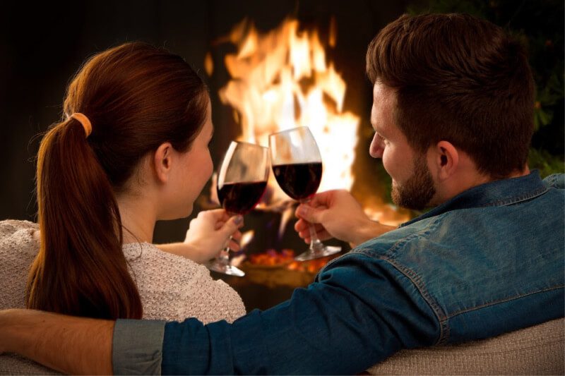 couple in front of a fireplace with wine