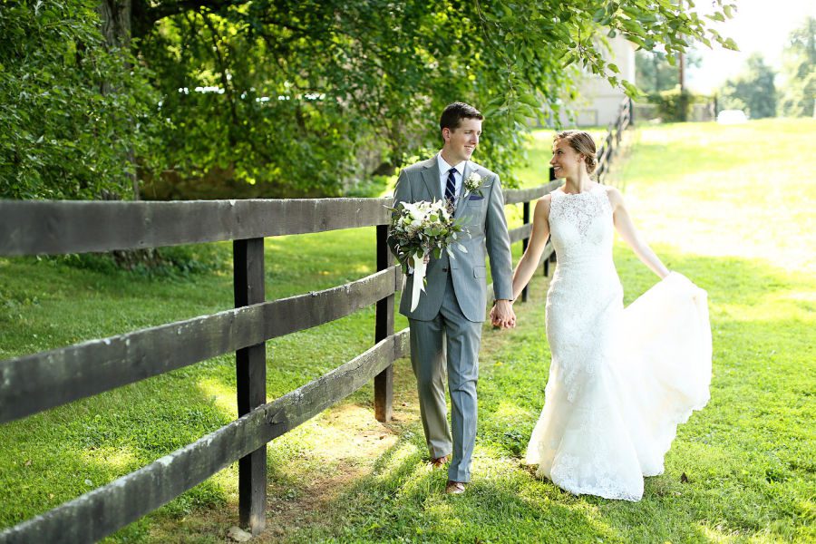 Husband and wife celebrating their virginia wedding in wine country, standing by a fence