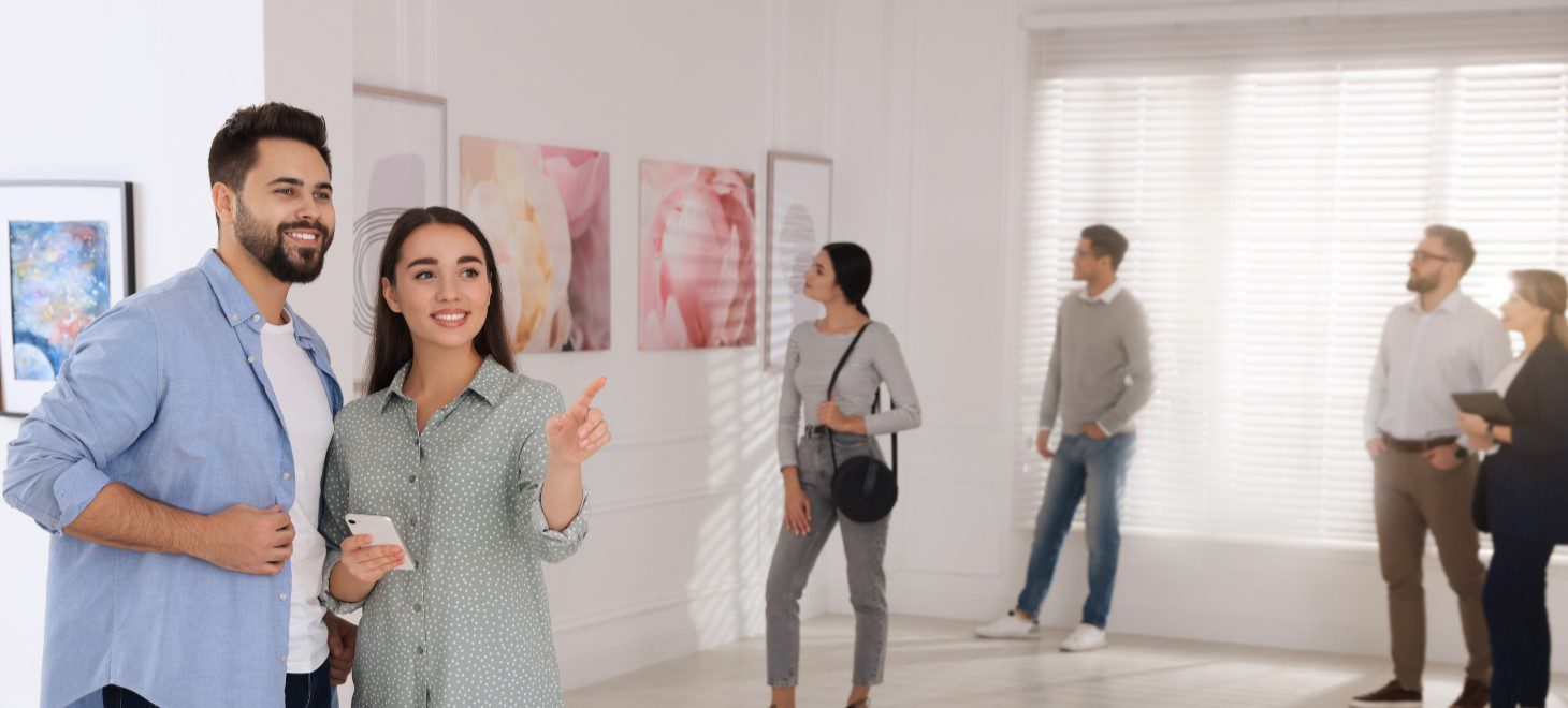 a couple looking at art in a gallery along with a crowd of people
