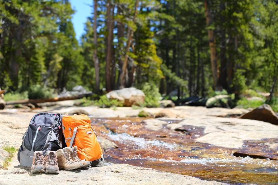 hiking back pack and boots next to a stream in the forest