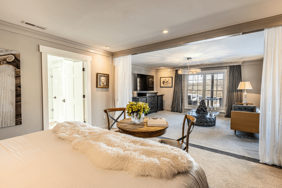 Modern neutral guest suite with a plush bed, faux-fur throw, and separate living area