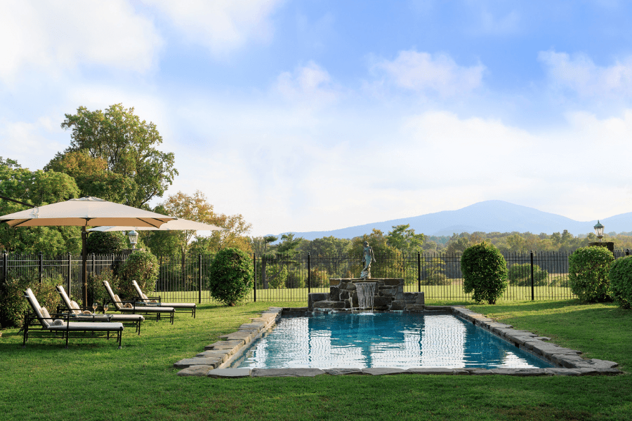 Luxury outdoor pool with stone waterfall, lounge chairs, and a mountain backdrop