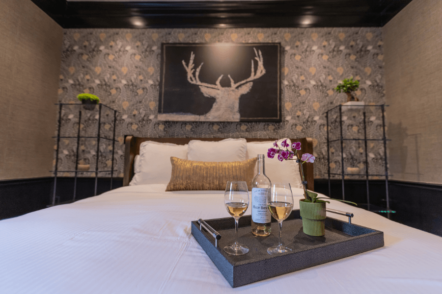 White wine and an orchid on a bed tray in a luxury bedroom with stag art